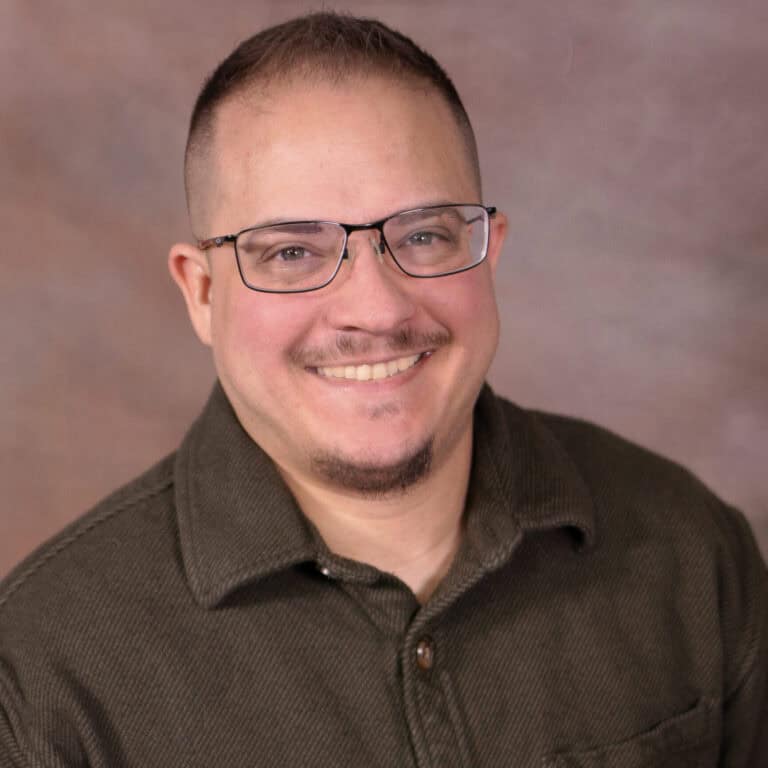 Portrait of Samuel Rhoades, a professional therapist, smiling in a casual setting.
