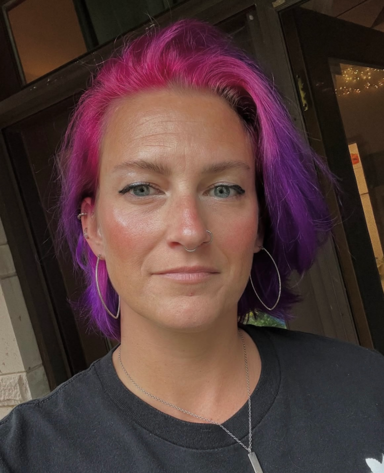 A therapist with striking pink and purple hair, showcasing bold hair, promoting mental health therapy for Transformative Therapy in Lansing, MI.